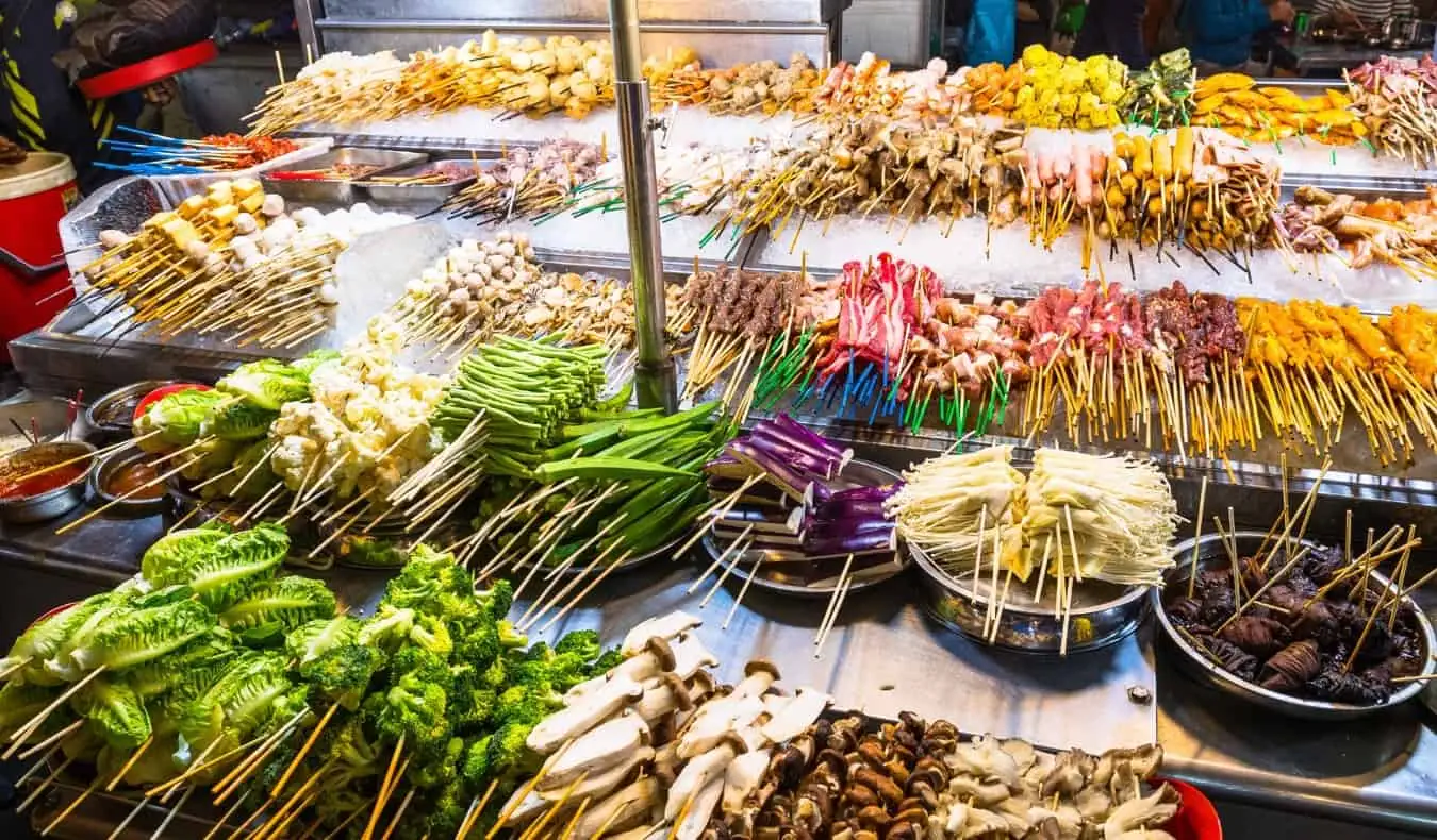 Brochettes de viande alignées sur un grill dans un étal de rue à Bangkok, Thaïlande