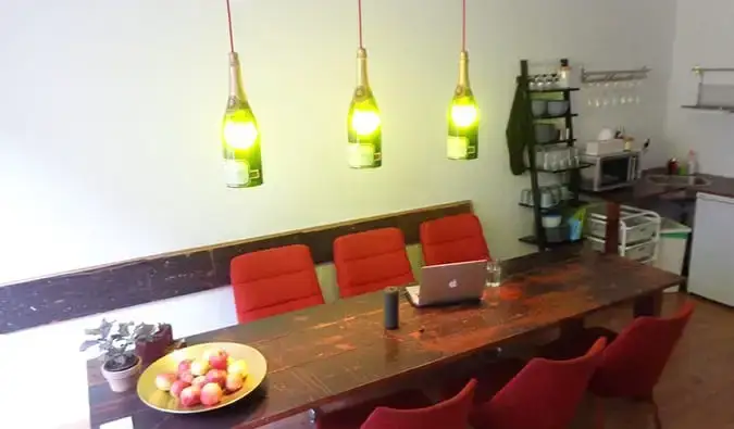 Coin cuisine avec longue table en bois et lampes suspendues faites de bouteilles de vin au Minimal Hostel Berlin, Berlin