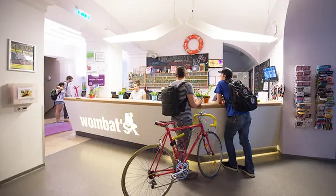 Deux personnes, dont une avec un vélo, s'enregistrant à la réception du Wombats Hostel, Budapest