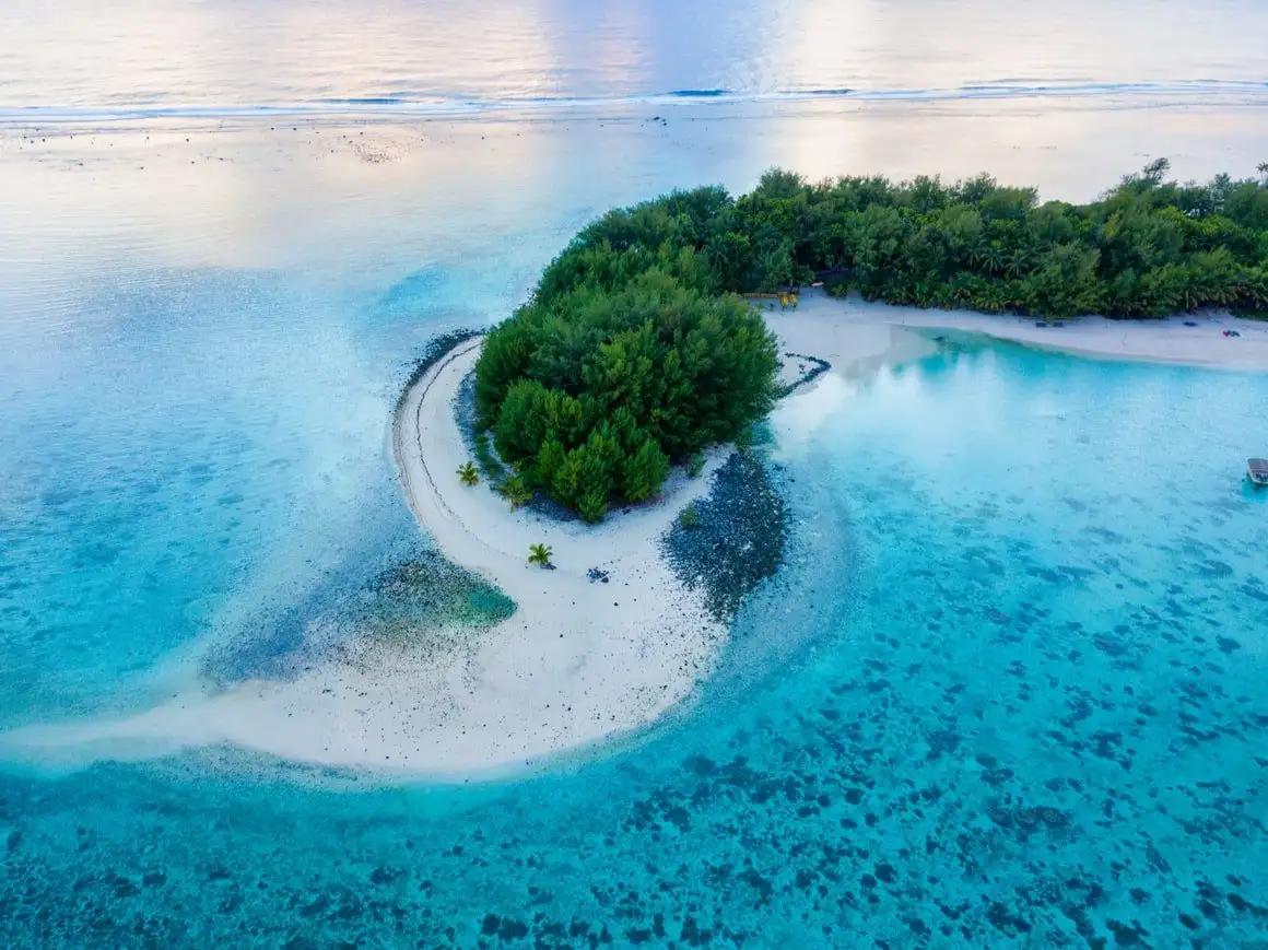 águas azuis cristalinas cercam uma ilha verdejante no Pacífico.