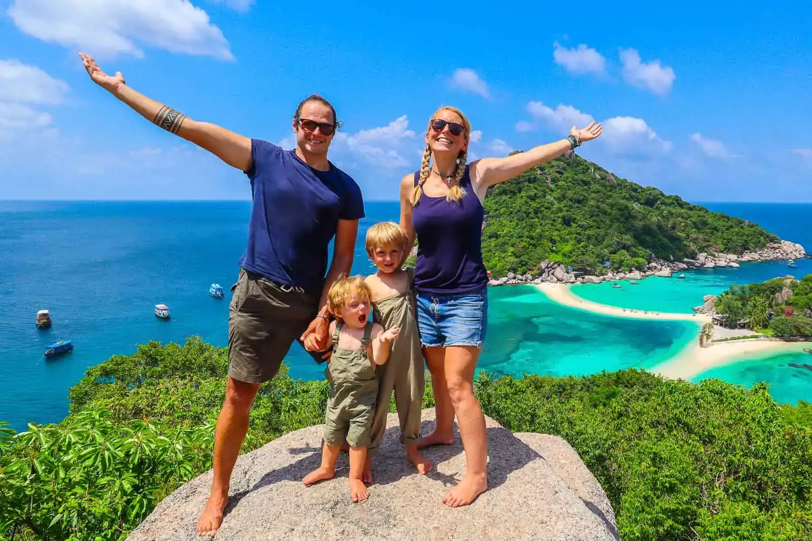 família mochileira em pé em um mirante na Tailândia com um mar azul brilhante abaixo