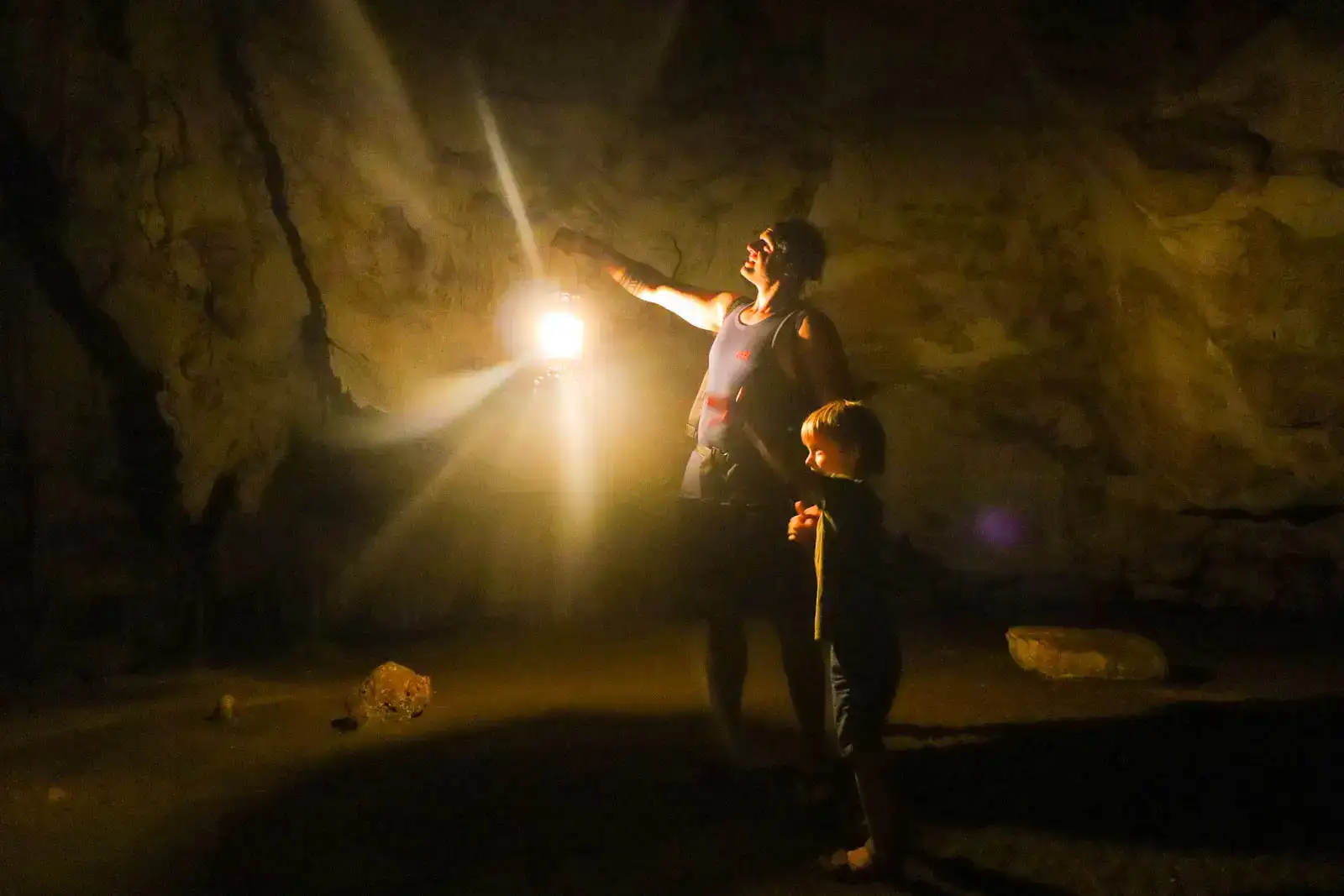 homem e seu filho explorando uma caverna escura enquanto vivem uma vida de viagens familiares em tempo integral