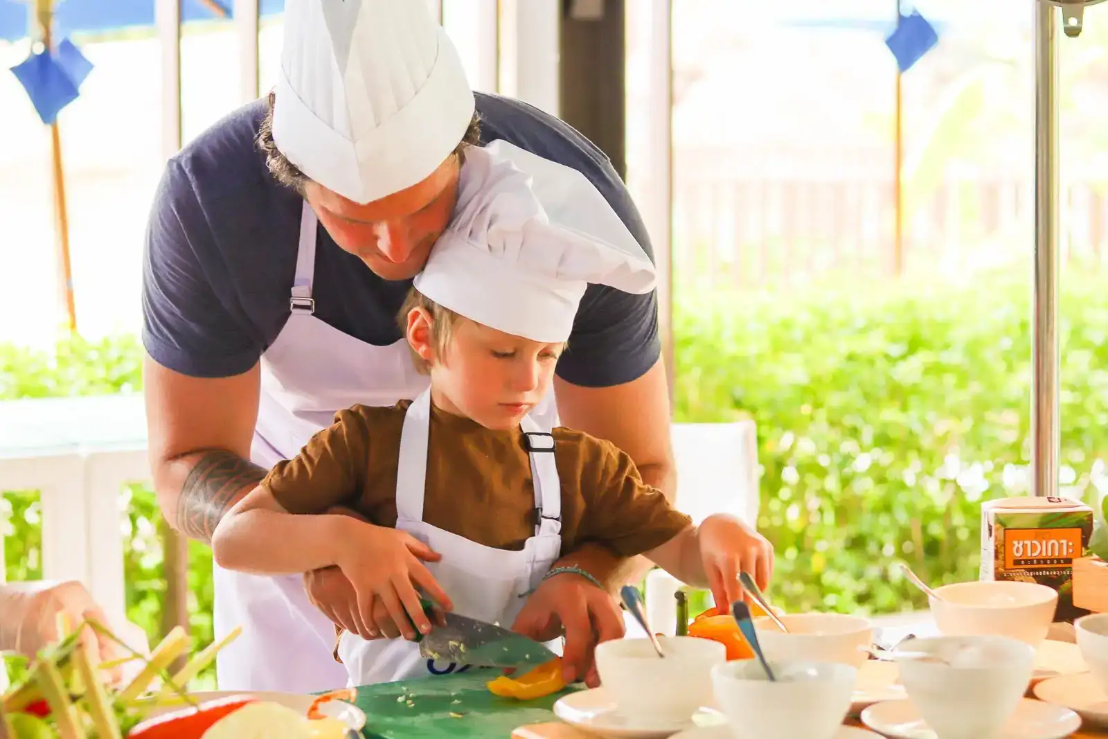 garoto com chapéu de chef branco aprendendo a cozinhar um prato com o pai