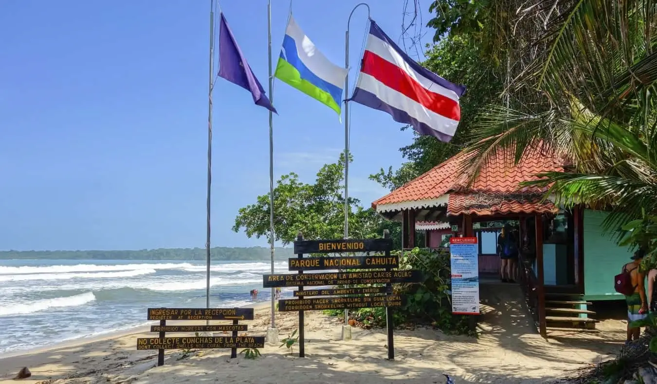 Entrée du parc national de Cahuita au Costa Rica avec des panneaux et des drapeaux flottants