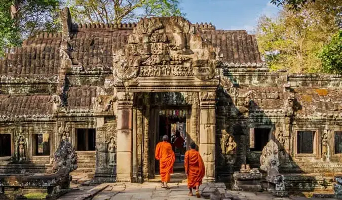 Deux moines en robes orange marchant dans un temple au Cambodge