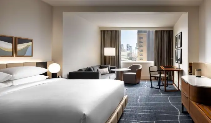 Um quarto amplo com cama king-size, sofá, área de estar e janelas amplas, todo decorado com design contemporâneo minimalista no hotel Park Hyatt em Toronto, Canadá