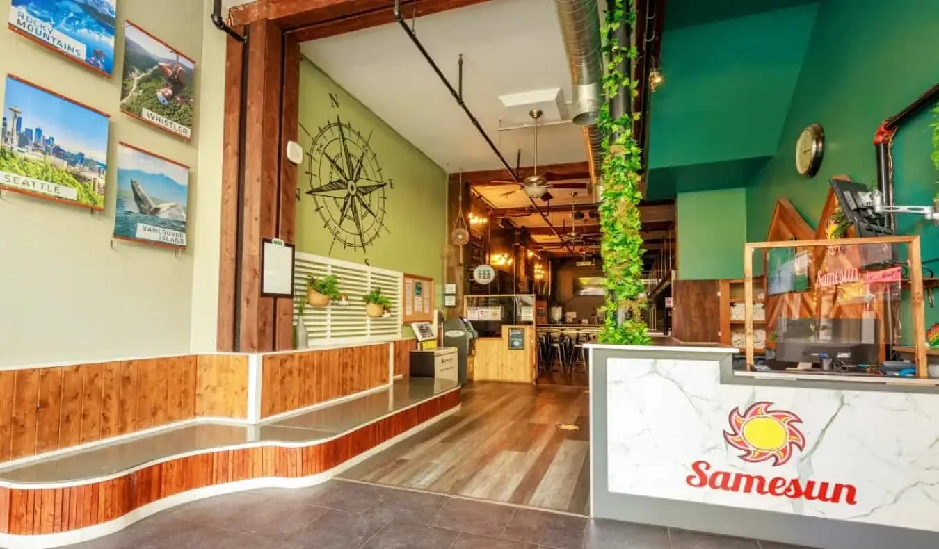 Réception et hall avec de hauts plafonds, de longues banquettes et des photographies sur le mur du Samesun Vancouver, Vancouver