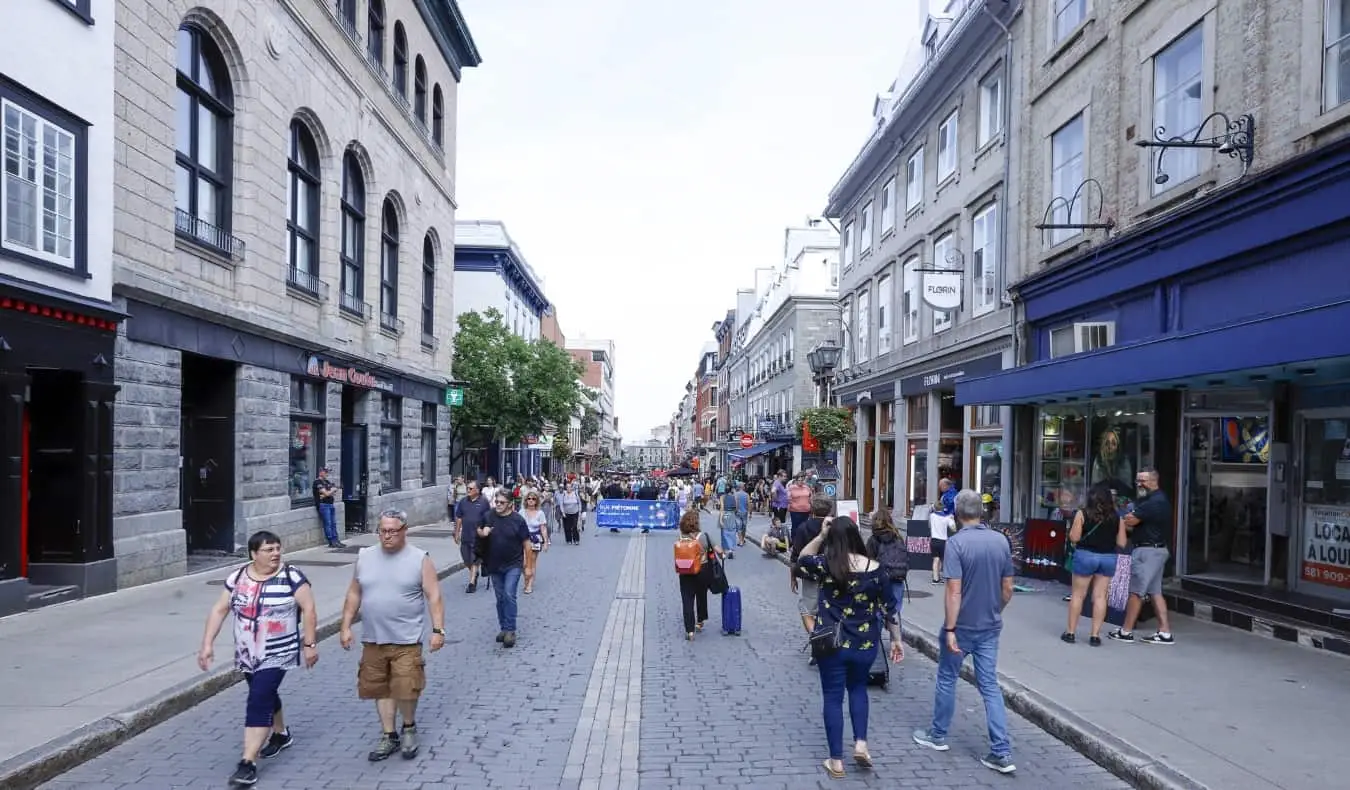 Les gens marchent au milieu de la rue pavée Saint-Jean en été quand il