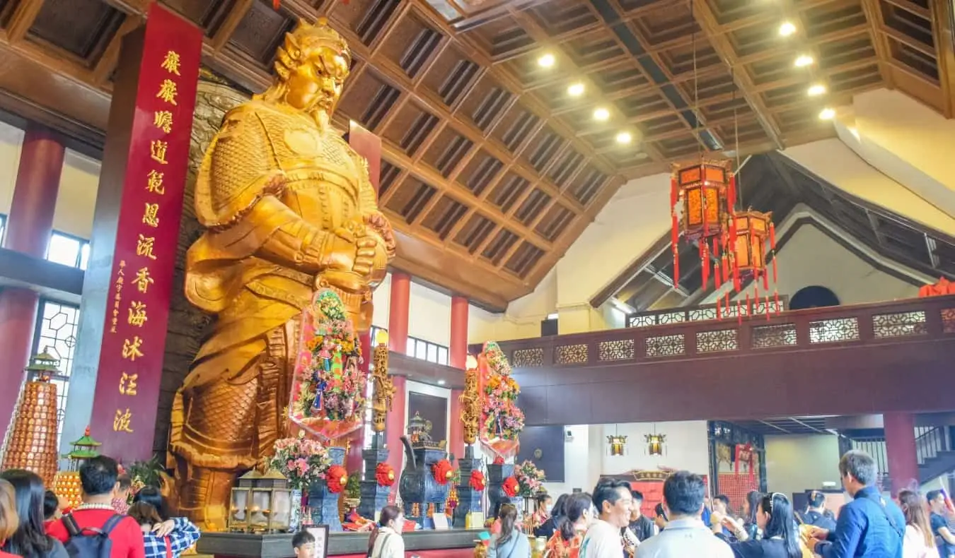 La grande statue dorée du commandant Che Kung avec des gens se pressant devant elle au temple Che Kung Miu à Hong Kong