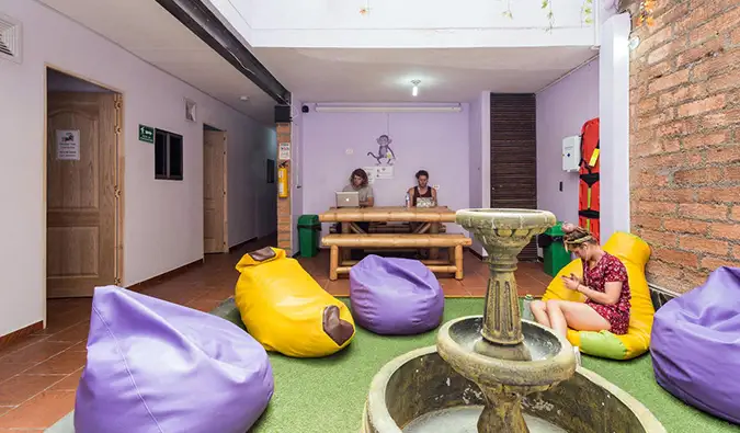 Espace commun avec des poufs violets et jaunes et des personnes travaillant sur des ordinateurs portables chez Purple Monkey, Medellin