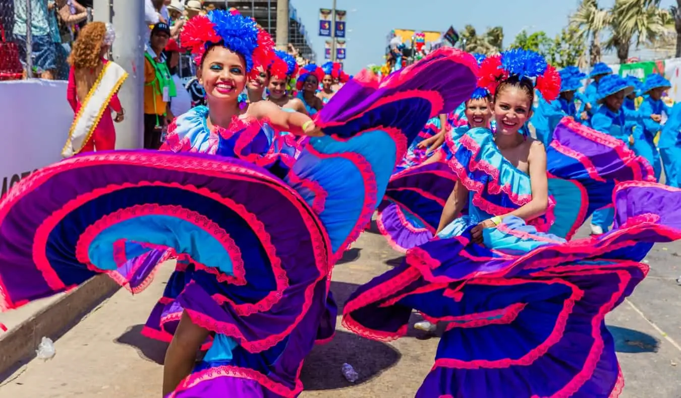 Femmes vêtues de robes rose vif et violettes, virevoltant pendant le carnaval de Barranquilla, Colombie