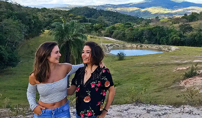 Celinne da Costa e uma nova amiga posando para uma foto em frente a uma paisagem pitoresca