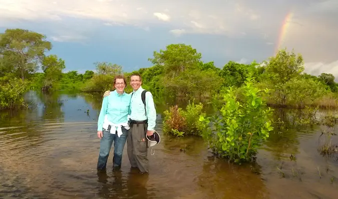 Um casal de idosos viajando por um país em desenvolvimento com um arco-íris ao fundo