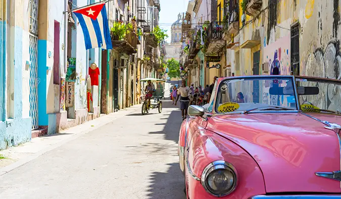 une voiture rose classique à Cuba dans une rue animée