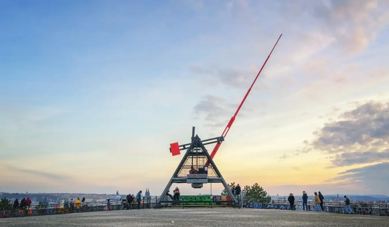 Un métronome géant en métal avec la longue main rouge pointant vers le ciel au coucher du soleil, à Prague, en République tchèque