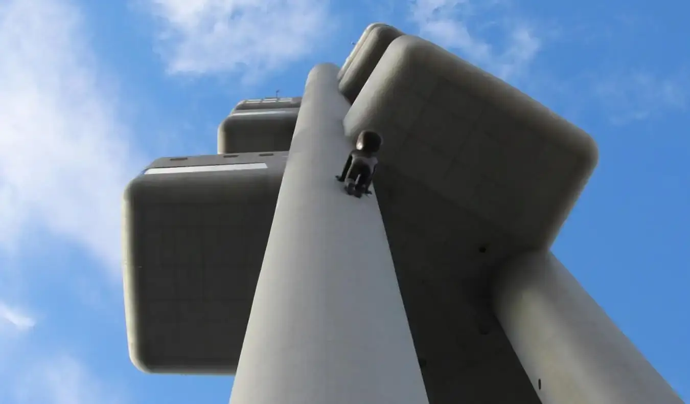 En regardant un pilier de la tour de télévision Zizkov tandis qu'un grand bébé sculpté noir y grimpe à Prague, en République tchèque