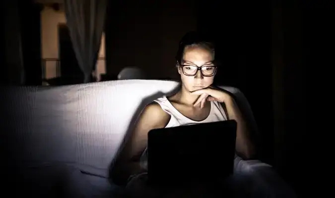 Seriøs kvindelig rejsende bruger sin bærbare computer i mørket