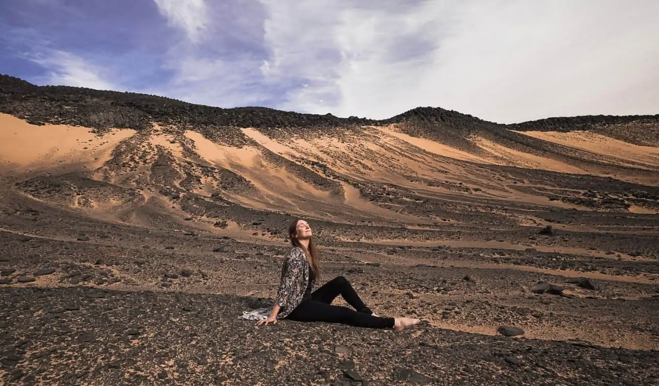 Monica, une voyageuse seule, assise dans le désert en Égypte, posant pour une photo
