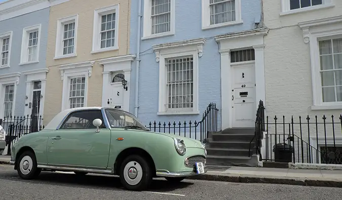 casas em tons pastéis com um carro antigo em Notting Hill