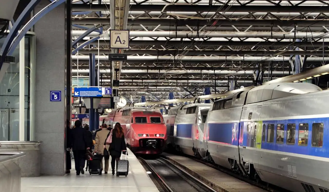 สถานีรถไฟที่มีคนขนสัมภาระข้างตู้รถไฟที่จอดอยู่