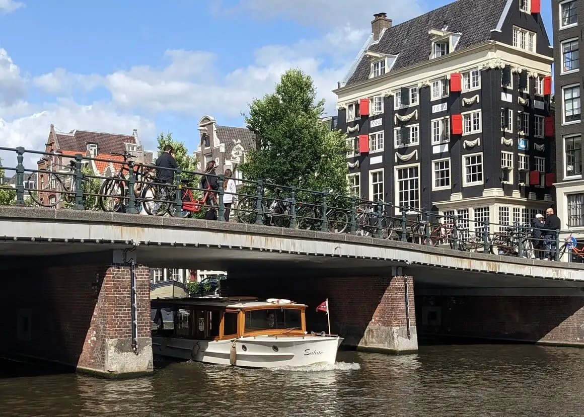 Barco de canal passando por baixo de uma ponte em Amsterdã em um dia ensolarado