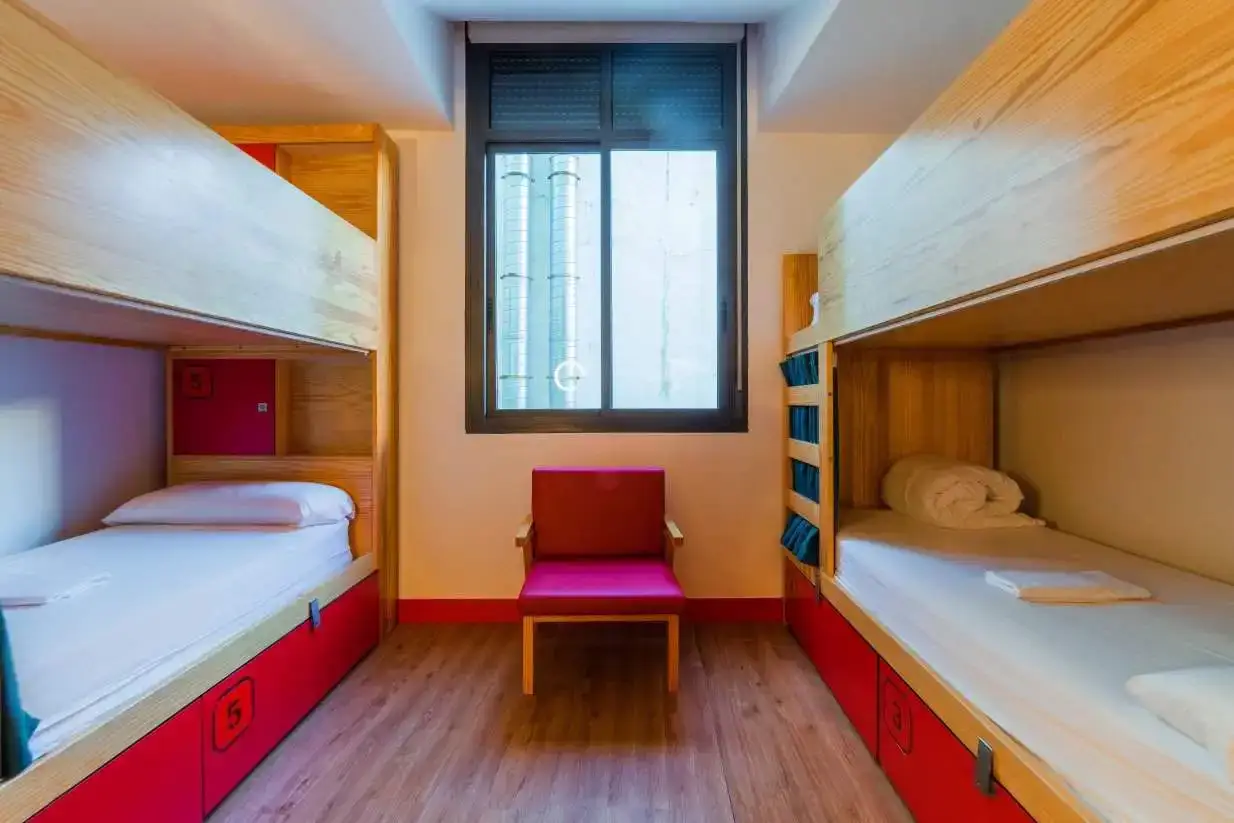 Dortoir avec 2 lits superposés en bois avec tiroirs de rangement rouges en dessous à l'Ok Hostel à Madrid, Espagne.