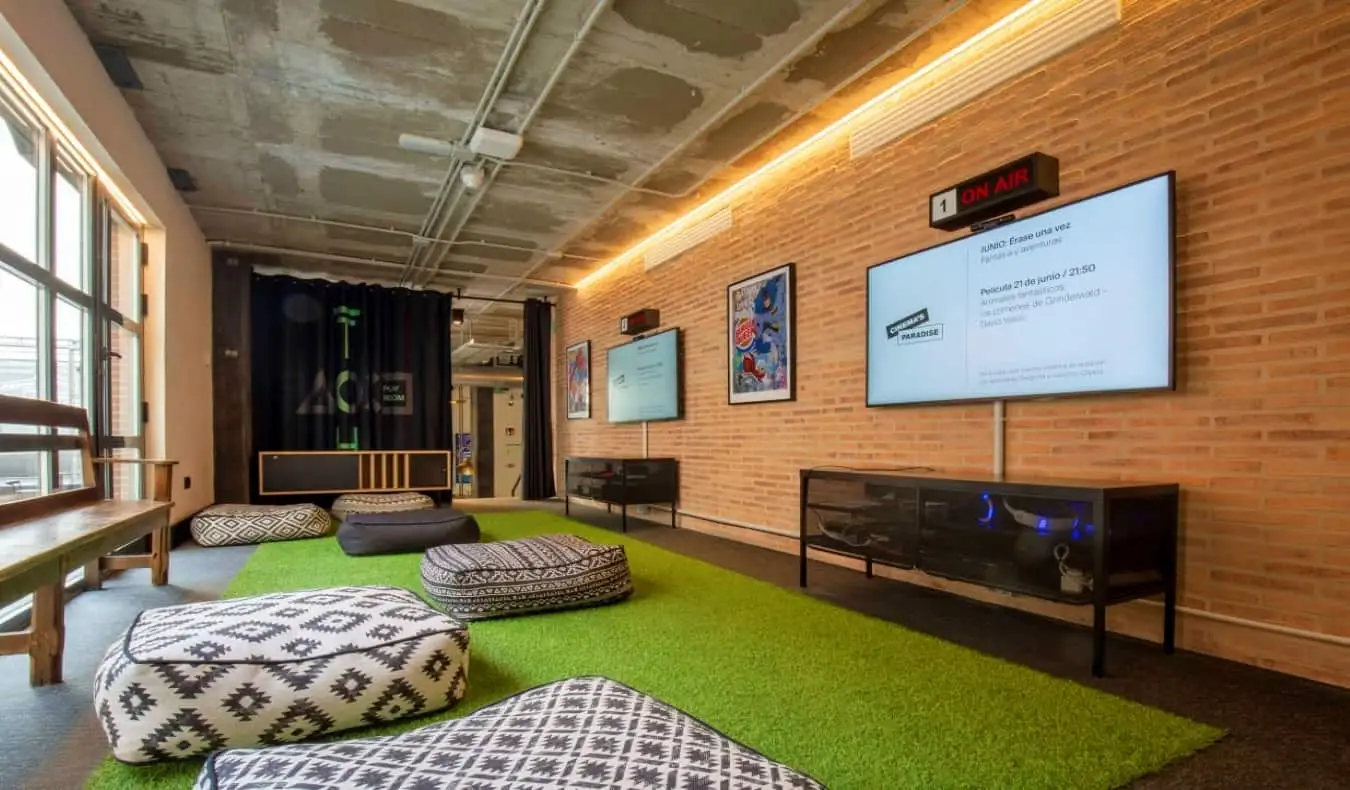 Salle de jeux avec de grandes télévisions à écran plat et de nombreux poufs à The Central House Lavapies, une auberge de jeunesse à Madrid, en Espagne.