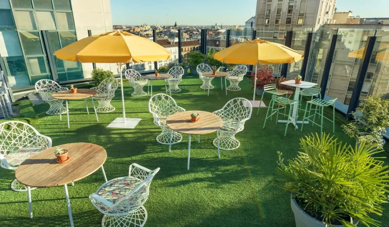 Le toit-terrasse de l'auberge Generator avec de nombreuses tables rondes et chaises, donnant sur les toits de Madrid, en Espagne.