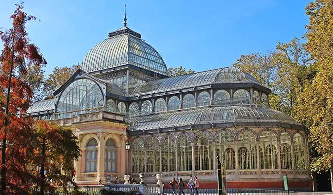 Žmonės, stovintys prie krištolo rūmų ir fontano Retiro parke, Madride, Ispanijoje saulėtą dieną