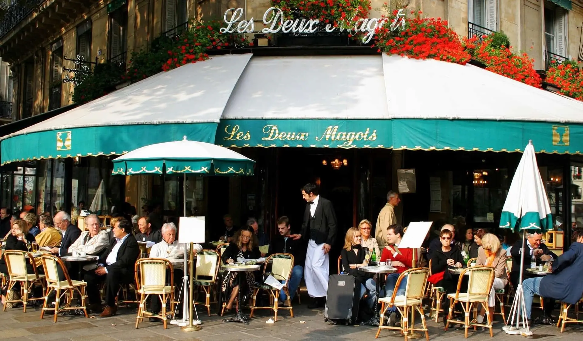 Moradores e turistas relaxando em Les Deux Magots em Paris, França
