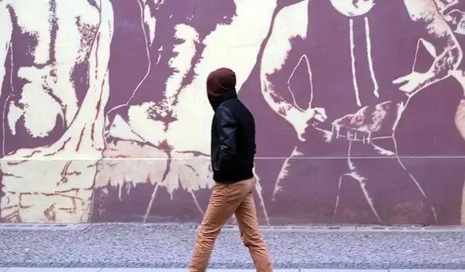 Hommes LGBT avec des sacs à dos se tenant la main avec amour dans une ville bondée d'outre-mer