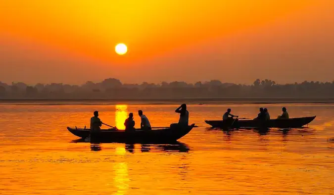 Un coucher de soleil doré près d'une rivière avec de petits bateaux de pêche en Inde