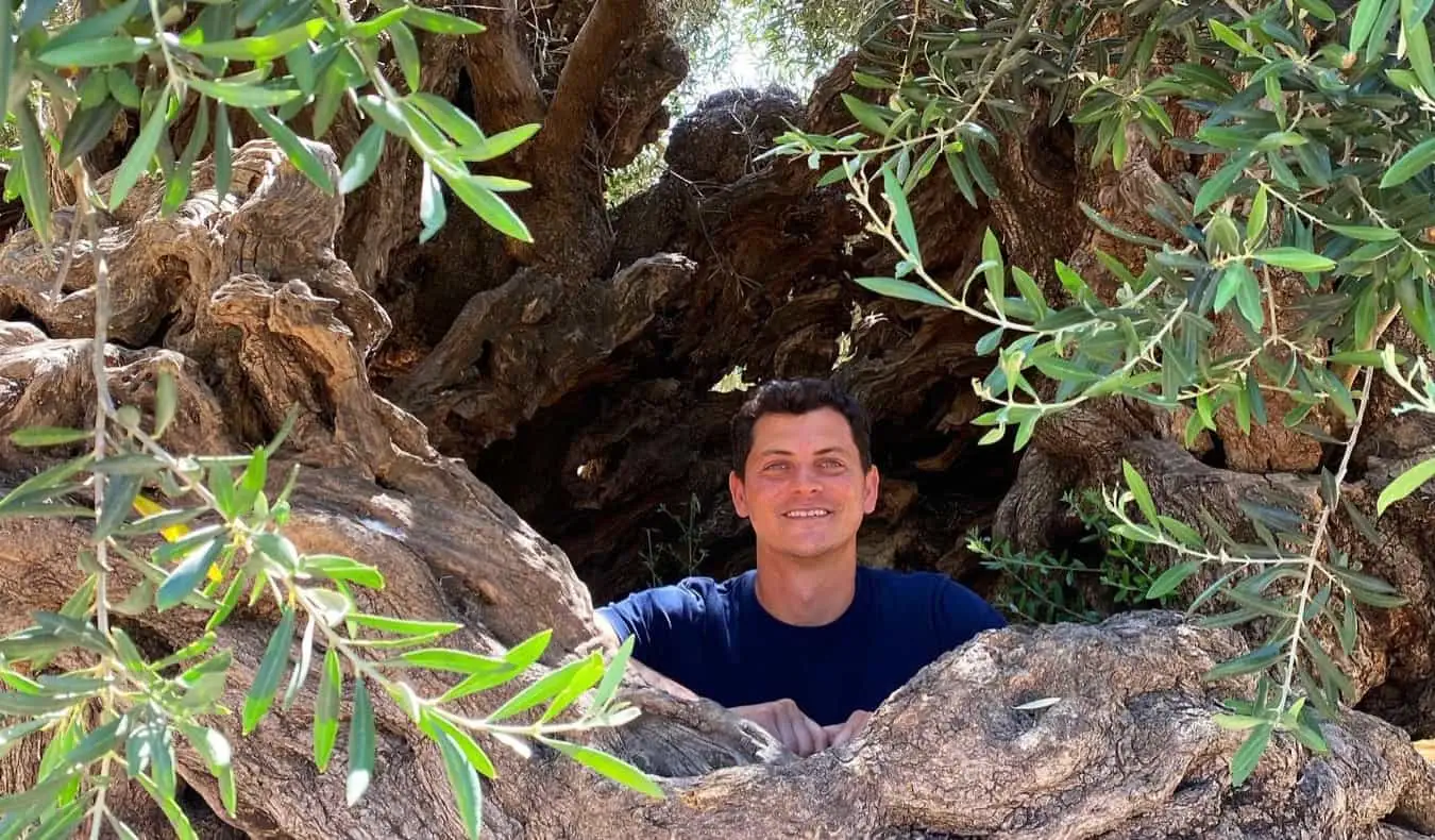 Nomadic Matt pózuje ve velké díře v lese při pěší turistice na Balkáně
