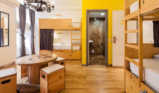Dortoir avec lits superposés en bois et petite table ronde au Yes! Auberge de jeunesse à Lisbonne
