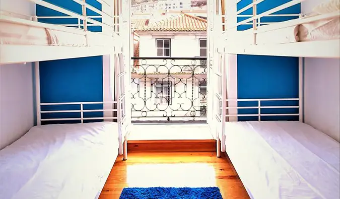 Lits superposés blancs de chaque côté de la fenêtre donnant sur les toits de Lisbonne chez We Love F. Tourists, Lisbonne