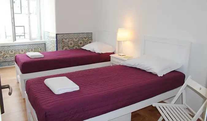 Deux lits jumeaux dans une chambre blanche au Lost Inn Lisbon, Lisbonne