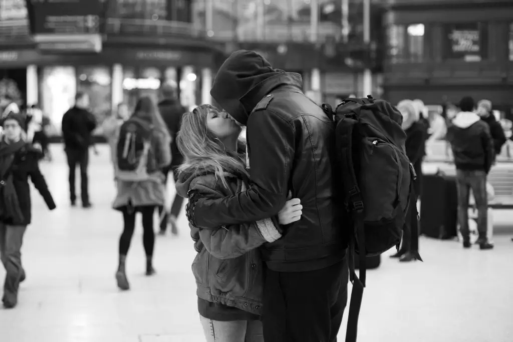 adorable photo en noir et blanc de routards s'embrassant au centre de transport pendant leur voyage