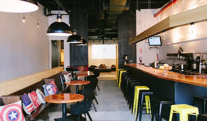 Espace commun avec petites tables et long bar en bois au Local NYC dans le Queens, New York.