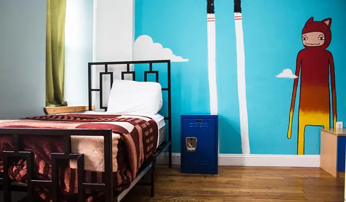 Lit simple dans la chambre avec fresque peinte sur le mur du NY Moore Hostel à New York.