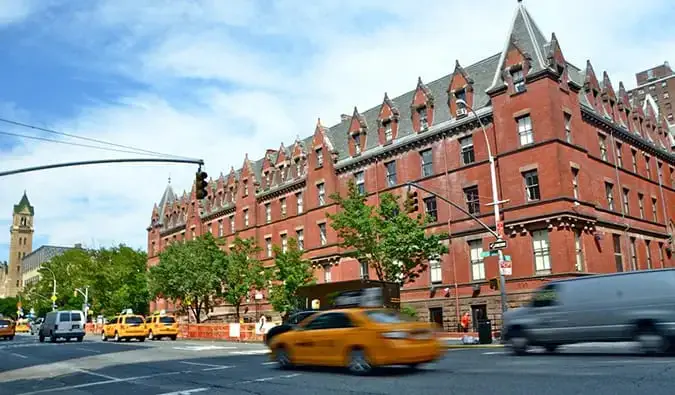 Grand bâtiment en brique avec des taxis jaunes passant par HI New York à New York