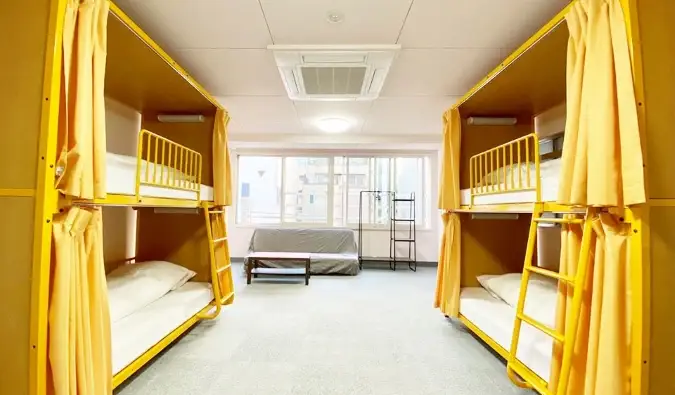Deux lits superposés jaunes avec rideaux d'intimité au Sakura Hotel Jimbocho à Tokyo, Japon