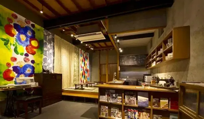 Salle commune avec réception, étagères et sièges au design japonais traditionnel à l'auberge Sheena et Ippei à Tokyo, Japon
