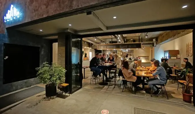 Des gens assis et parlant dans le bar vus à travers les baies vitrées de l'Imano Tokyo Hostel à Tokyo, Japon