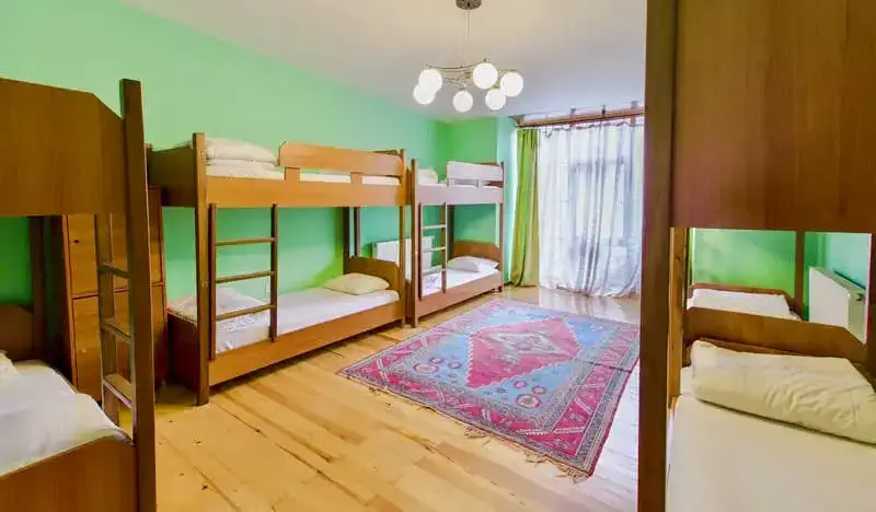 En sovsal på Cheers Hostel med gröna väggar och mysiga våningssängar
