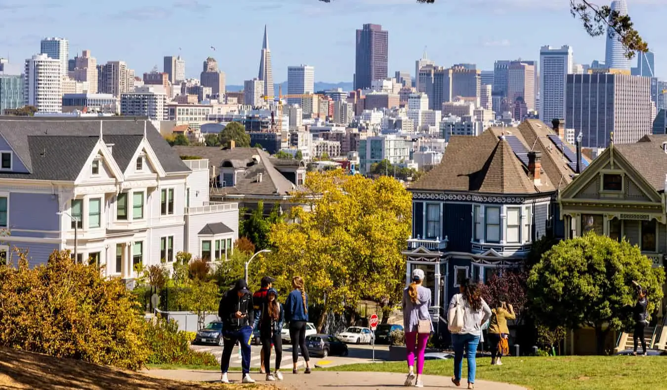 Les gens se promènent sous le soleil de San Francisco avec l'imposant centre-ville au loin