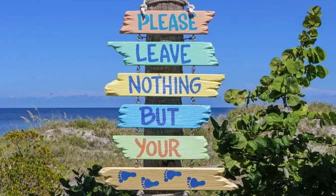 Un panneau près de la plage qui dit de ne laisser que des empreintes de différentes couleurs
