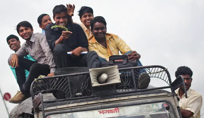 একটি গাড়ির উপরে স্থানীয়দের একটি দল যখন এটি চলে