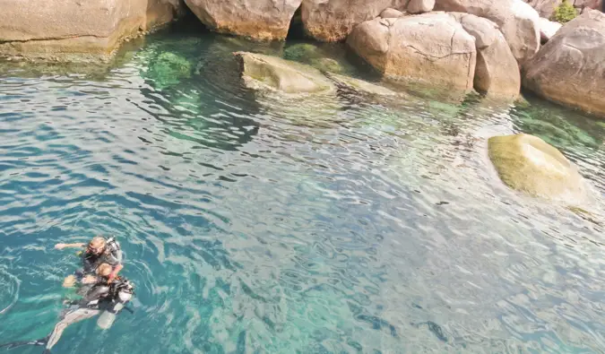 Alex em Wanderland mergulhando na água com um grupo de amigos perto de Koh Tao, Tailândia