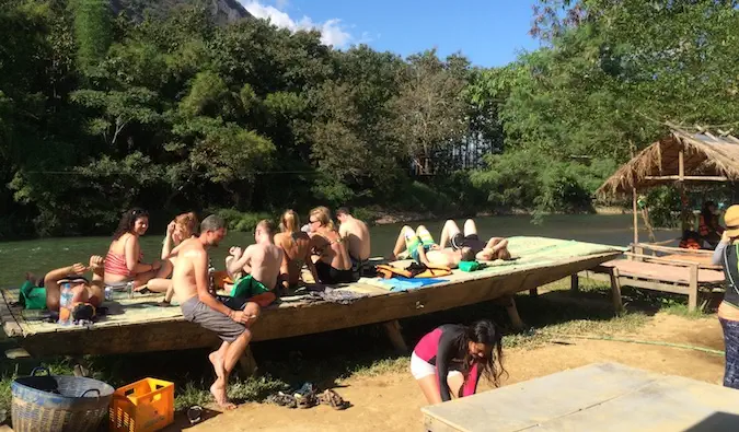 Viaggiatori con lo zaino in spalla che oziano in riva all'acqua a Vang Vieng, Laos