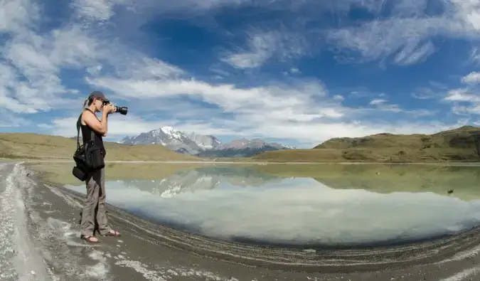 O femeie care stă în natură făcând fotografii cu o cameră profesională